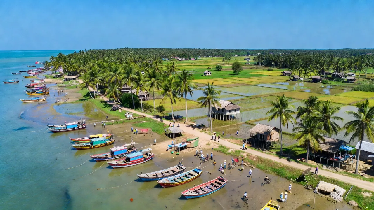 Cảnh quan huyện Duyên Hải, tỉnh Trà Vinh với bờ biển, cây cọ và thuyền đánh cá truyền thống.
